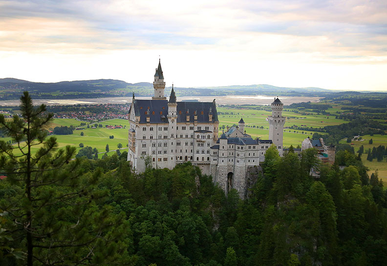 The Neuschwanstein Castle in Hohenschwangau, Germany.  The castle is a 19th-century Romanesque Revival palace on a rugged hill above the village of Hohenschwangau near Füssen in southwest Bavaria, Germany. The palace was commissioned by Ludwig II of Bavaria as a retreat and in honour of Richard Wagner.  The castle was intended as a home for the king, until he died in 1886. It was open to the public shortly after his death.  Since then more than 61 million people have visited Neuschwanstein Castle.